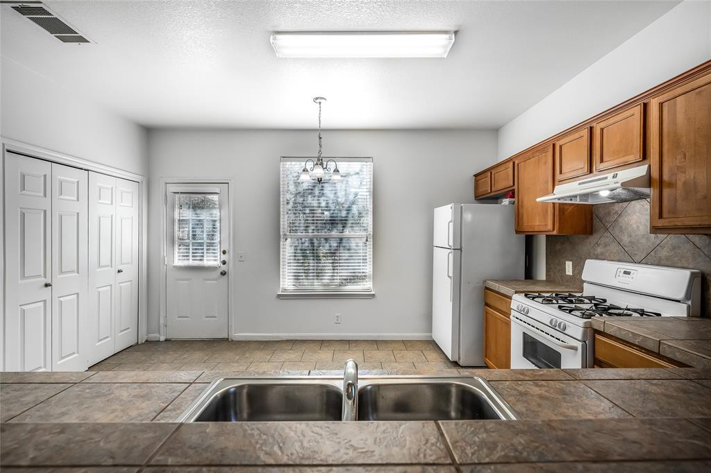 2518 Allred Drive, Unit A Austin, TX 78748 - Photo 3 of 16 Kitchen featuring white appliances, wood finish cabinetry, tile counters, suspended lighting, and a textured ceiling