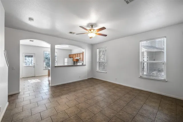 a view of an empty room with a window and a kitchen
