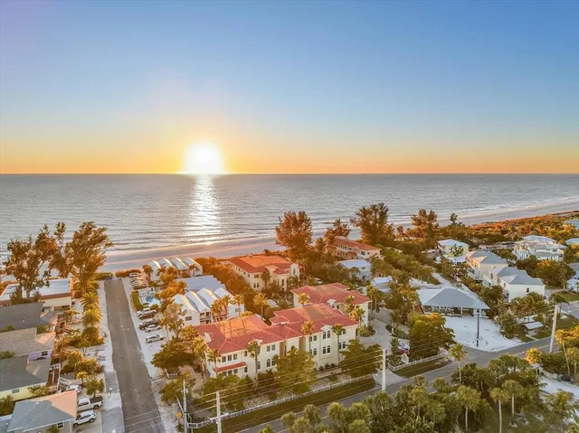 an aerial view of ocean and residential houses with outdoor space