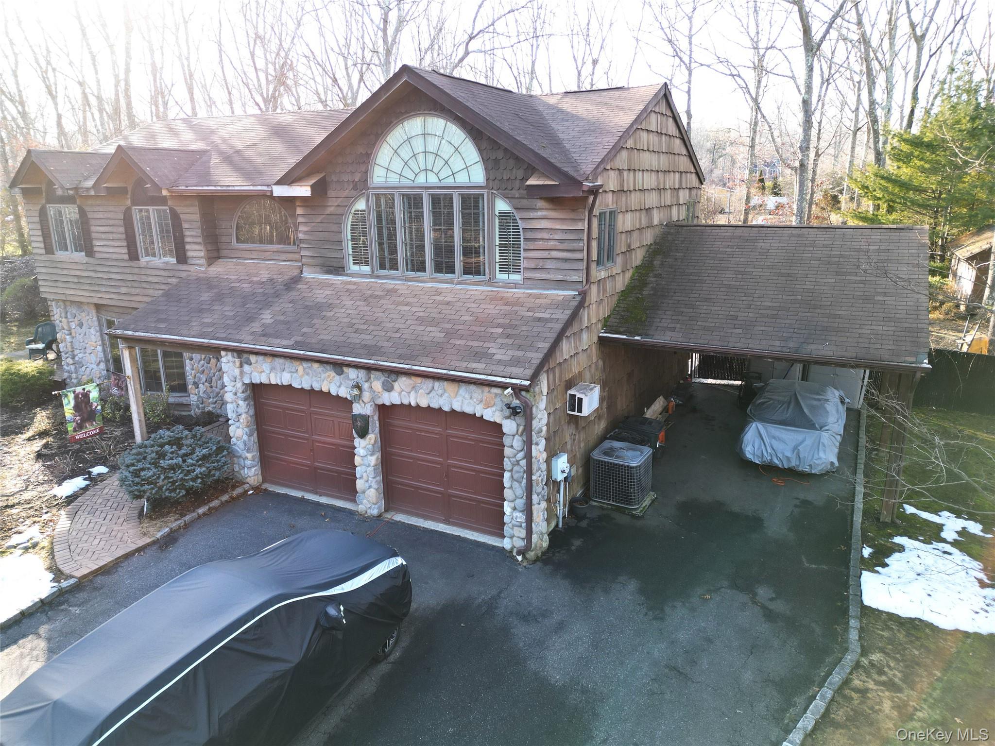 35 Hastings Drive Ridge, NY 11961 - Photo 2 of 39 View of front facade with stone siding, a garage, asphalt driveway, roof with shingles, and an AC wall unit