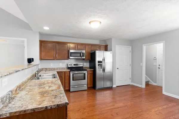a large kitchen with stainless steel appliances granite countertop a refrigerator and a stove top oven