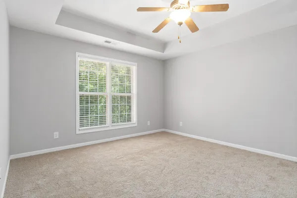 an empty room with chandelier fan and windows