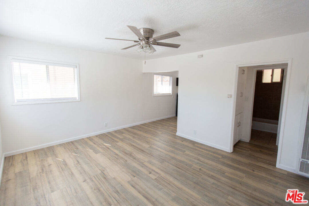 5267 Ithaca Avenue Los Angeles, CA 90032 - Photo 7 of 25 an empty room with wooden floor a ceiling fan and windows