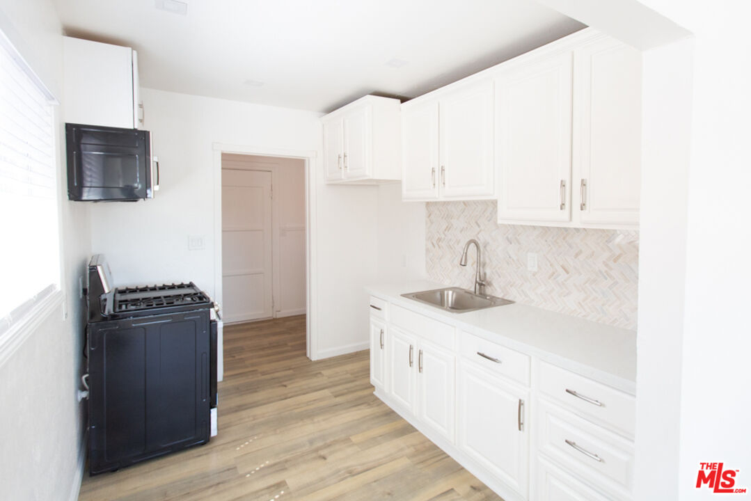 5267 Ithaca Avenue Los Angeles, CA 90032 - Photo 9 of 25 a kitchen with granite countertop a sink stove and refrigerator