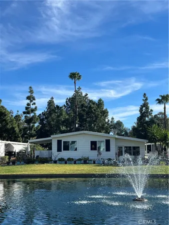 a front view of a house with a garden and lake view