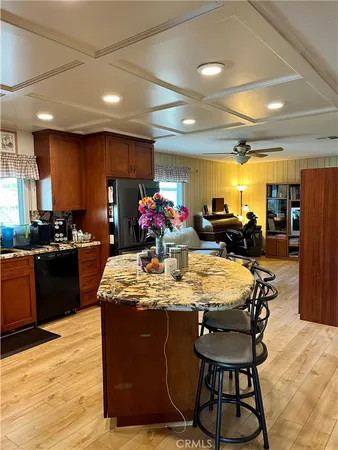a kitchen with stainless steel appliances kitchen island granite countertop a stove a refrigerator a sink dishwasher and a dining table with wooden floor