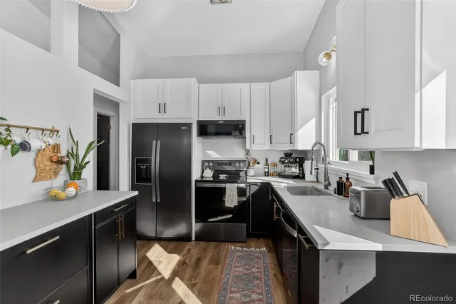 a kitchen with stainless steel appliances granite countertop a refrigerator a sink a stove and a refrigerator with wooden floor