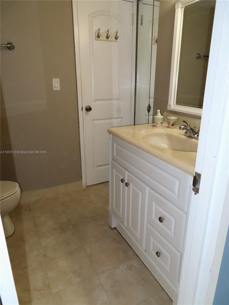5701 Collins Avenue, Unit 304 Miami Beach, FL 33140 - Photo 15 of 42 a bathroom with a granite countertop sink a toilet and mirror