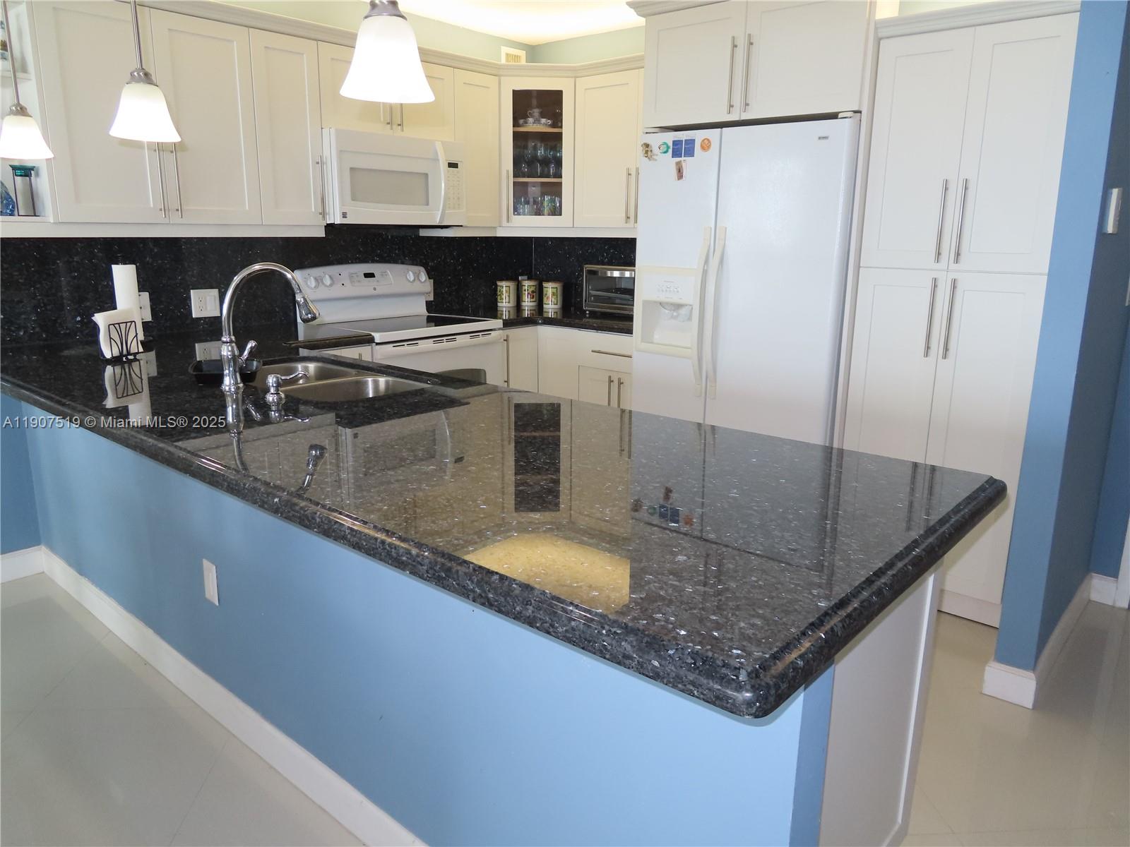 5701 Collins Avenue, Unit 304 Miami Beach, FL 33140 - Photo 10 of 42 a kitchen with stainless steel appliances granite countertop a sink a refrigerator and a counter space