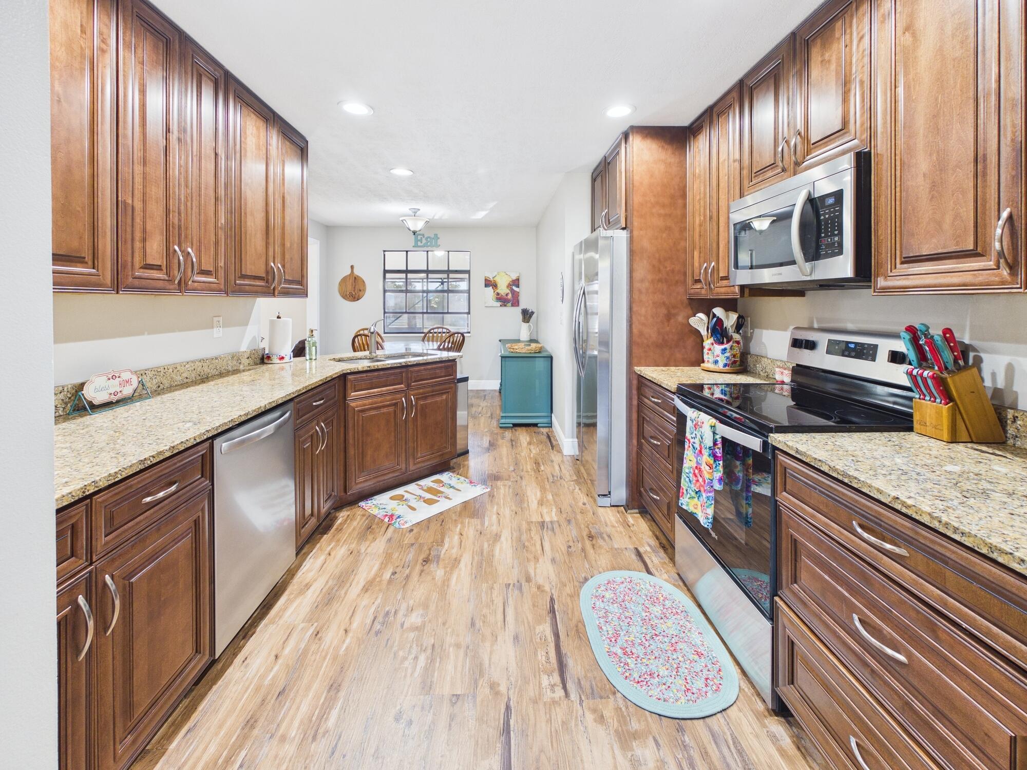 755 Southwest 85th Avenue Okeechobee, FL 34974 - Photo 19 of 99 a large kitchen with stainless steel appliances granite countertop wooden cabinets a sink dishwasher a stove and a refrigerator