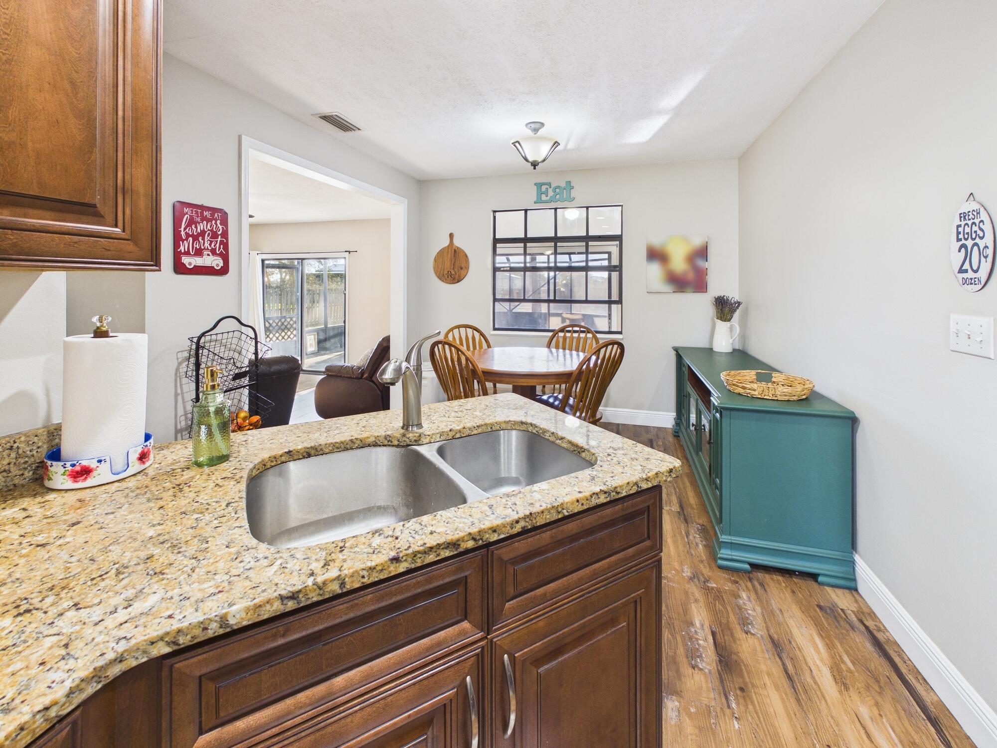 755 Southwest 85th Avenue Okeechobee, FL 34974 - Photo 22 of 99 a kitchen with granite countertop a sink and a wooden floor