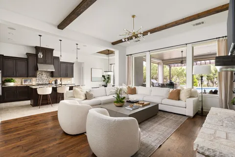 a living room with furniture kitchen view and a large window
