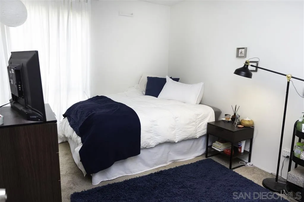 3583 Ruffin Road, Unit 214 San Diego, CA 92123 - Photo 6 of 12 a bedroom with a bed a mirror and a flat tv screen on a table