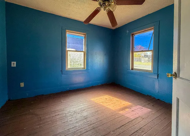 a view of an empty room with window and wooden floor
