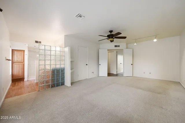 an empty room with chandelier fan and windows