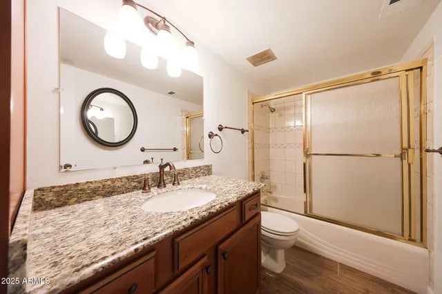 a bathroom with a granite countertop sink toilet a mirror and shower