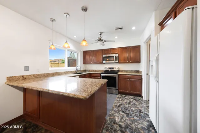a kitchen with stainless steel appliances granite countertop a sink a stove and a refrigerator