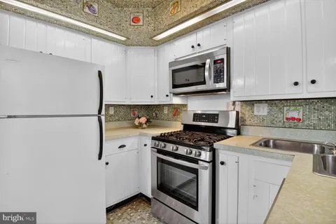 a kitchen with stainless steel appliances granite countertop white cabinets a stove a microwave and a refrigerator