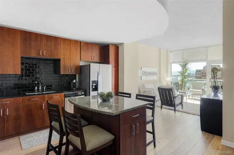 a dining hall with stainless steel appliances granite countertop a stove a refrigerator a sink a dining table and chairs with wooden floor