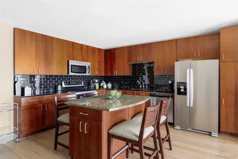 a kitchen with stainless steel appliances granite countertop a stove a refrigerator a sink a dining table and chairs