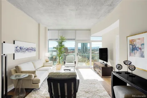 a living room with furniture a flat screen tv and a floor to ceiling window