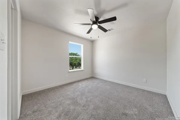 an empty room with windows and fan