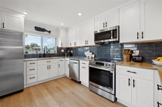 a kitchen with stainless steel appliances granite countertop a refrigerator and wooden cabinets