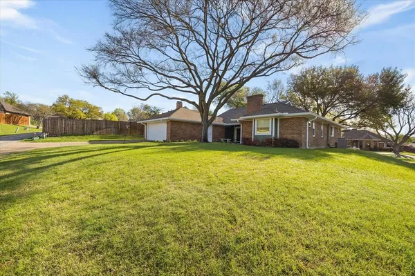 a view of a house with a big yard and large trees