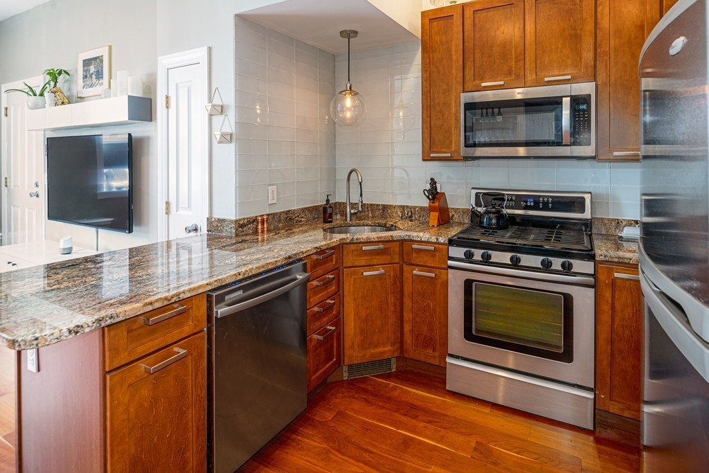 295 D Street, Unit 1 Boston, MA 02127 - Photo 4 of 13 a kitchen with stainless steel appliances granite countertop a stove microwave and sink