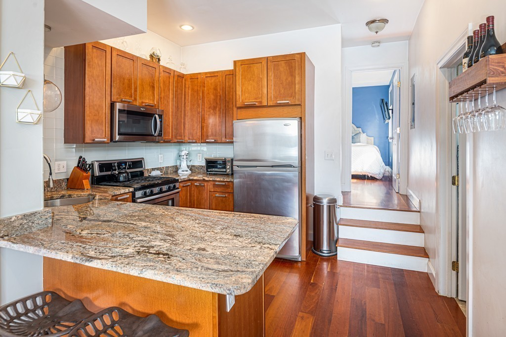 295 D Street, Unit 1 Boston, MA 02127 - Photo 5 of 13 a kitchen with stainless steel appliances granite countertop a refrigerator a stove and a sink