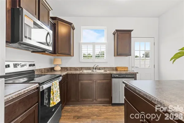 a kitchen with stainless steel appliances granite countertop a stove a sink and a microwave