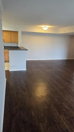 a view of kitchen and empty room with wooden floor and windows