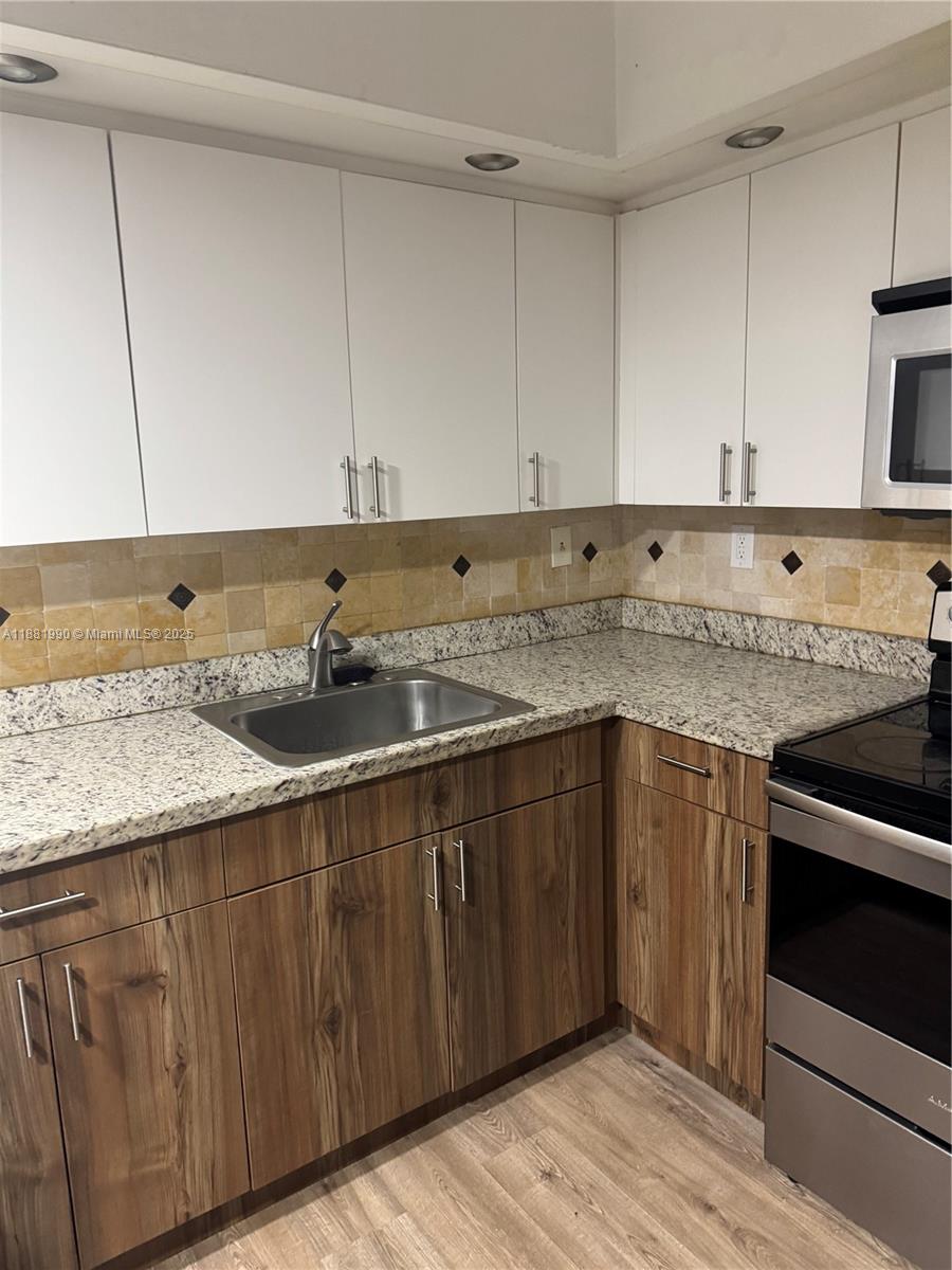 8811 Southwest 132nd Place, Unit 401CW Miami, FL 33186 - Photo 3 of 10 a kitchen with granite countertop a sink and cabinets