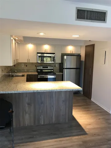 a kitchen with kitchen island a counter top and refrigerator