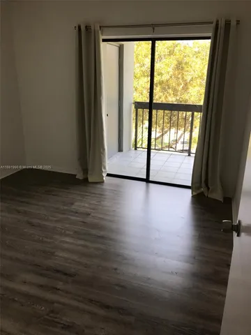 a view of a room with wooden floor and a window