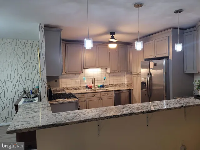 a kitchen with granite countertop a sink a counter space cabinets and stainless steel appliances