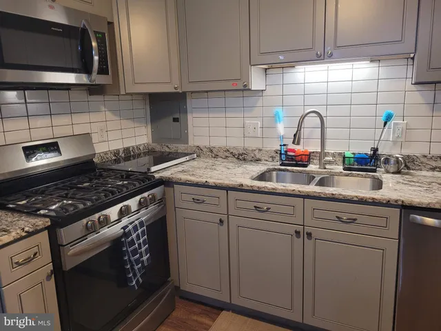 a kitchen with granite countertop a sink stove and cabinets