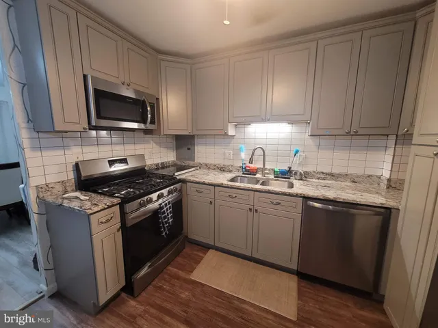 a kitchen with granite countertop wooden cabinets and a stove top oven
