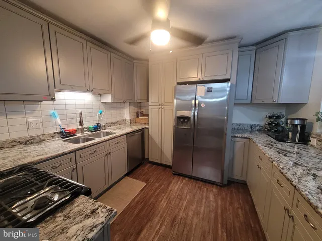 a kitchen with granite countertop wooden floors stainless steel appliances and sink