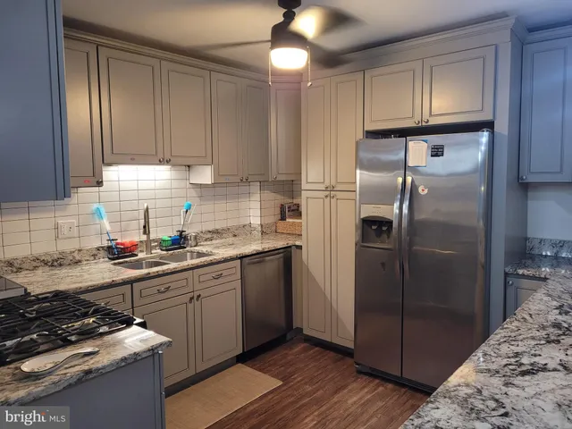 a kitchen with stainless steel appliances granite countertop a refrigerator a sink and wooden cabinets