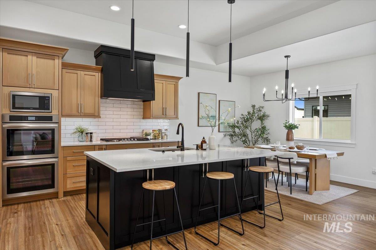 924 Trapper Peak Road Kimberly, ID 83341 - Photo 10 of 40 Kitchen with stainless steel appliances, light wood finished floors, dual tone cabinetry, a kitchen island with sink, and a breakfast bar