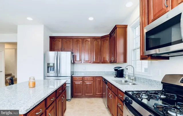 a kitchen with stainless steel appliances granite countertop a sink stove refrigerator and cabinets