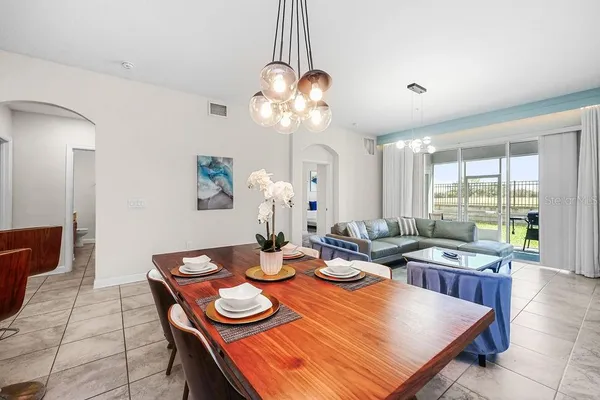 a view of a dining room with furniture a chandelier and large windows