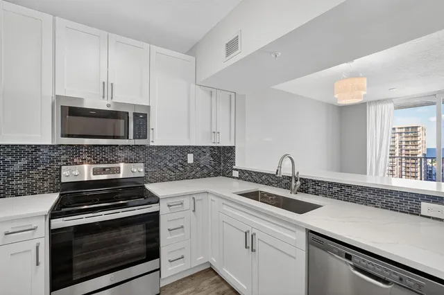 a kitchen with sink a microwave a stove and cabinets