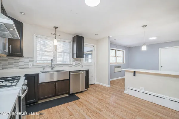 a large kitchen with stainless steel appliances granite countertop a sink dishwasher a stove and white countertops with wooden floor