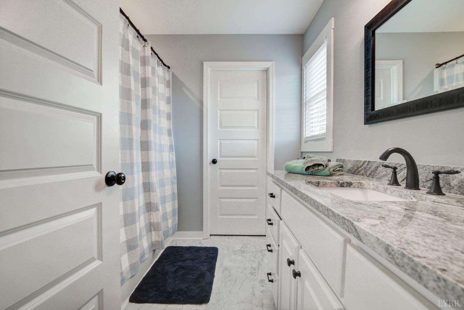 701 Winfall Road Rustburg, VA 24554 - Photo 24 of 38 a bathroom with a granite countertop sink a mirror a vanity and a shower