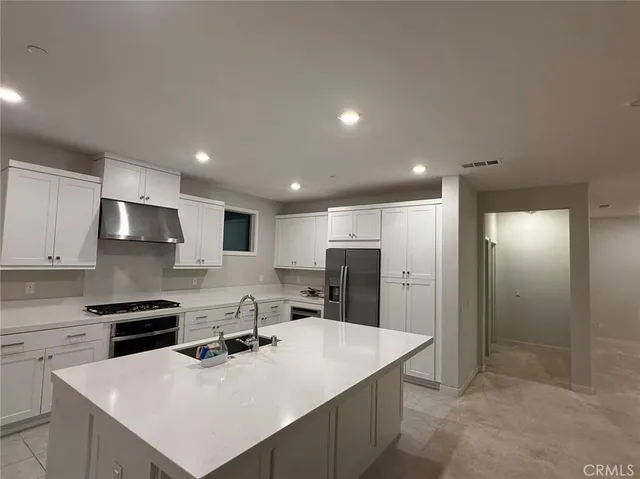 a kitchen with a sink a stove a refrigerator and white cabinets