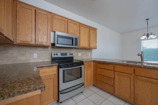 a kitchen with granite countertop cabinets stainless steel appliances and a sink