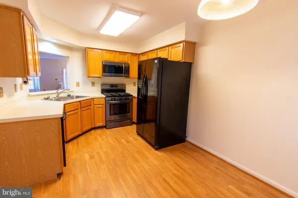 a kitchen with stainless steel appliances granite countertop a refrigerator a sink dishwasher and white cabinets with wooden floor