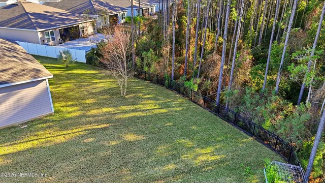 a view of a white house with a yard plants and palm trees